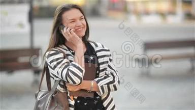 年轻快乐兴奋的笑女在手机<strong>上说</strong>话，女孩在街<strong>上</strong>挥手，城市的背景。